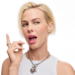 Model with a platinum blonde bob wearing glossy pink Smashbox O-Gloss, raising one finger with a surprised expression.
